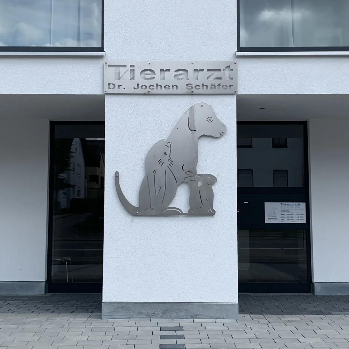 Praxiseingang mit Edelstahl-Schild und Tierfiguren