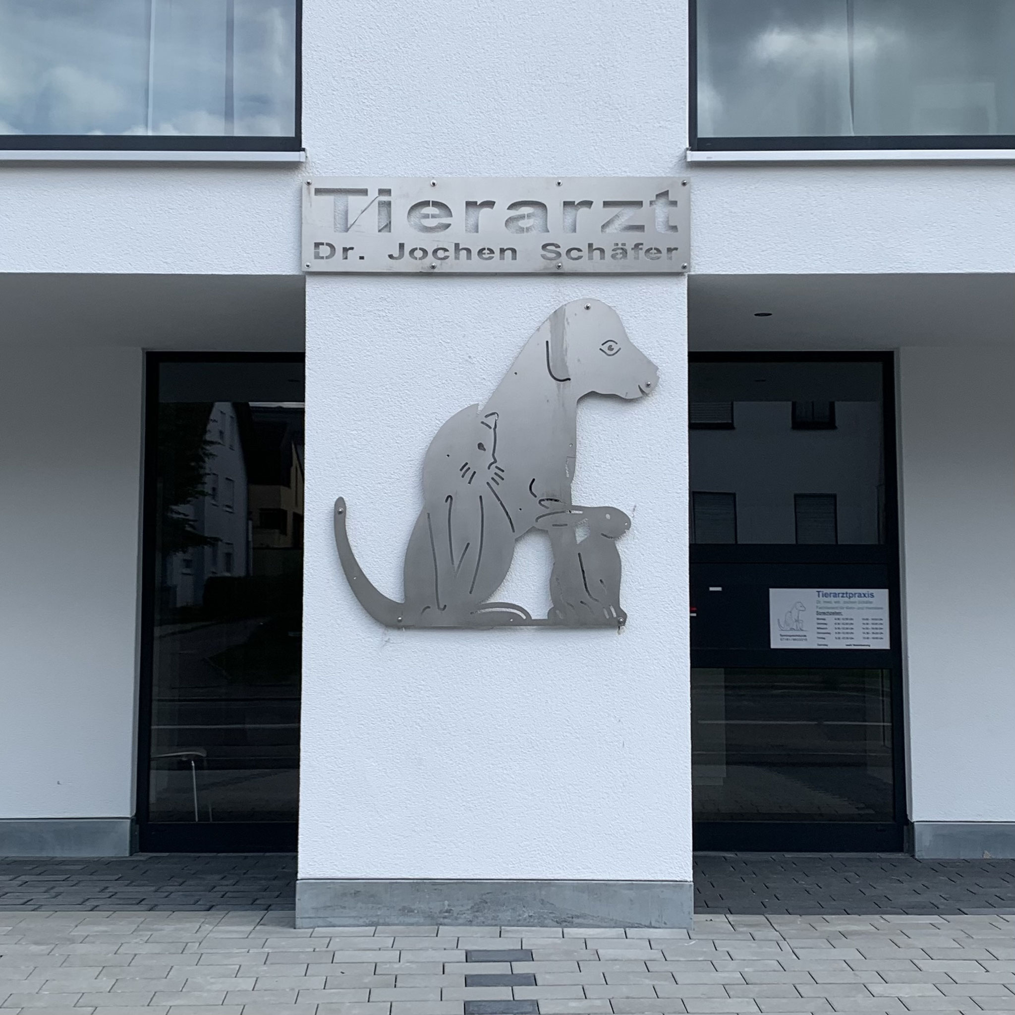 Praxiseingang mit Edelstahl-Schild und Tierfiguren